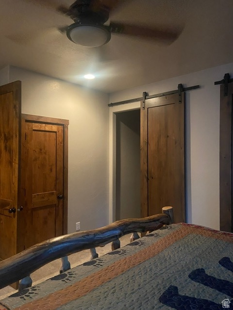 MASTER BEDROOM WALK IN CLOSET AND LOCKED STORAGE CLOSET  bedroom featuring a barn door and ceiling fan