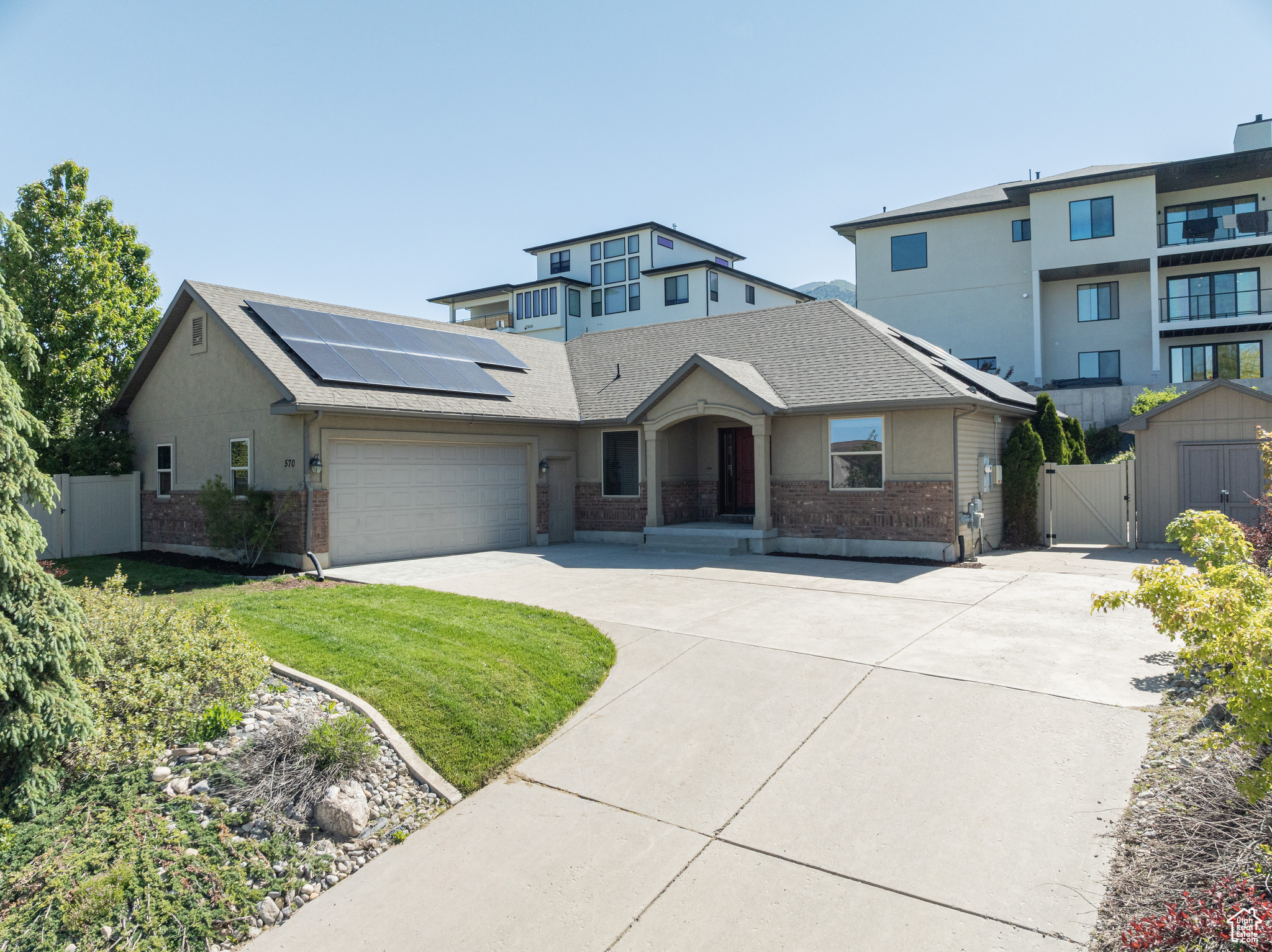 View of front of house featuring a garage, solar panels, and a front lawn