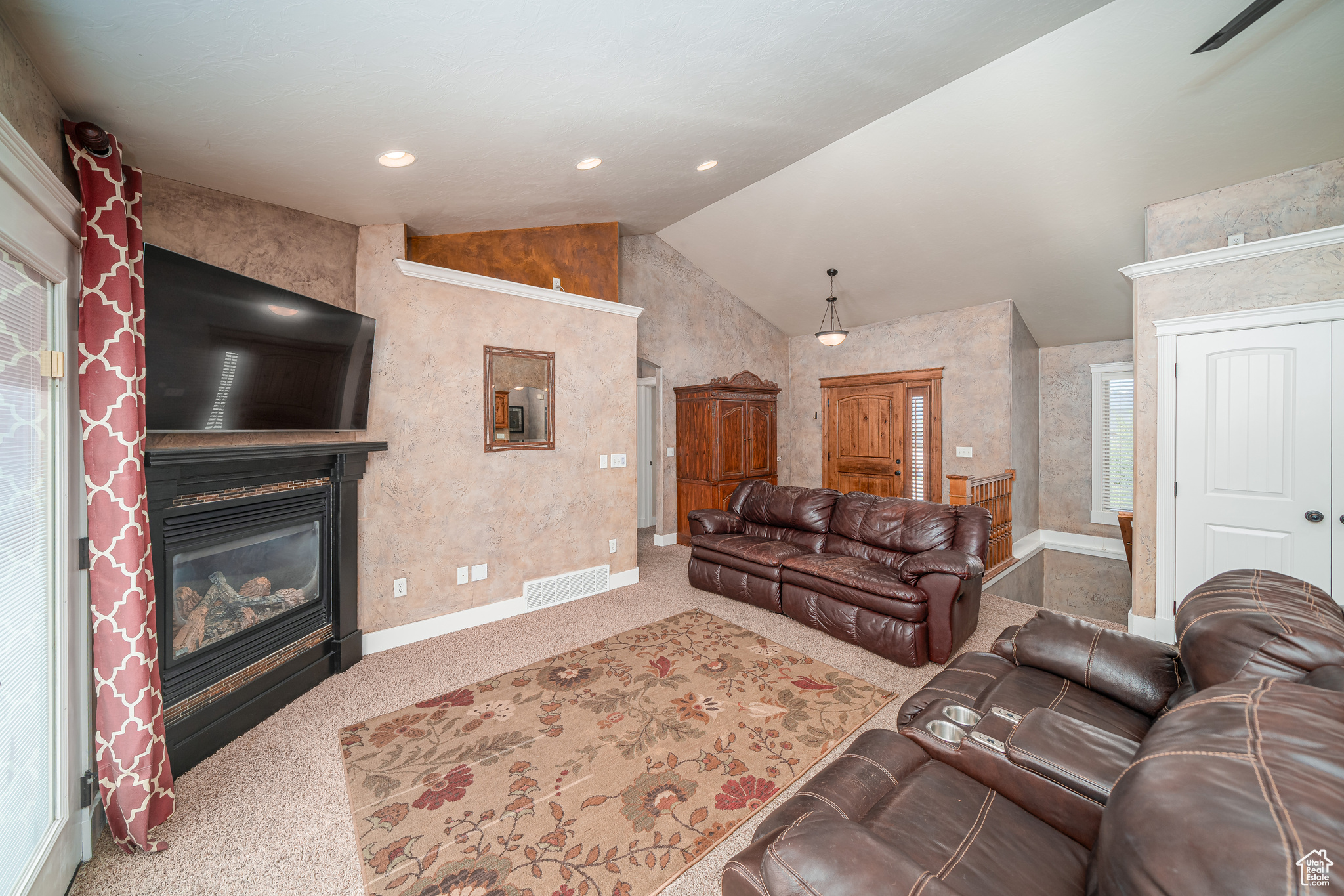 Carpeted living room with high vaulted ceiling and a large fireplace