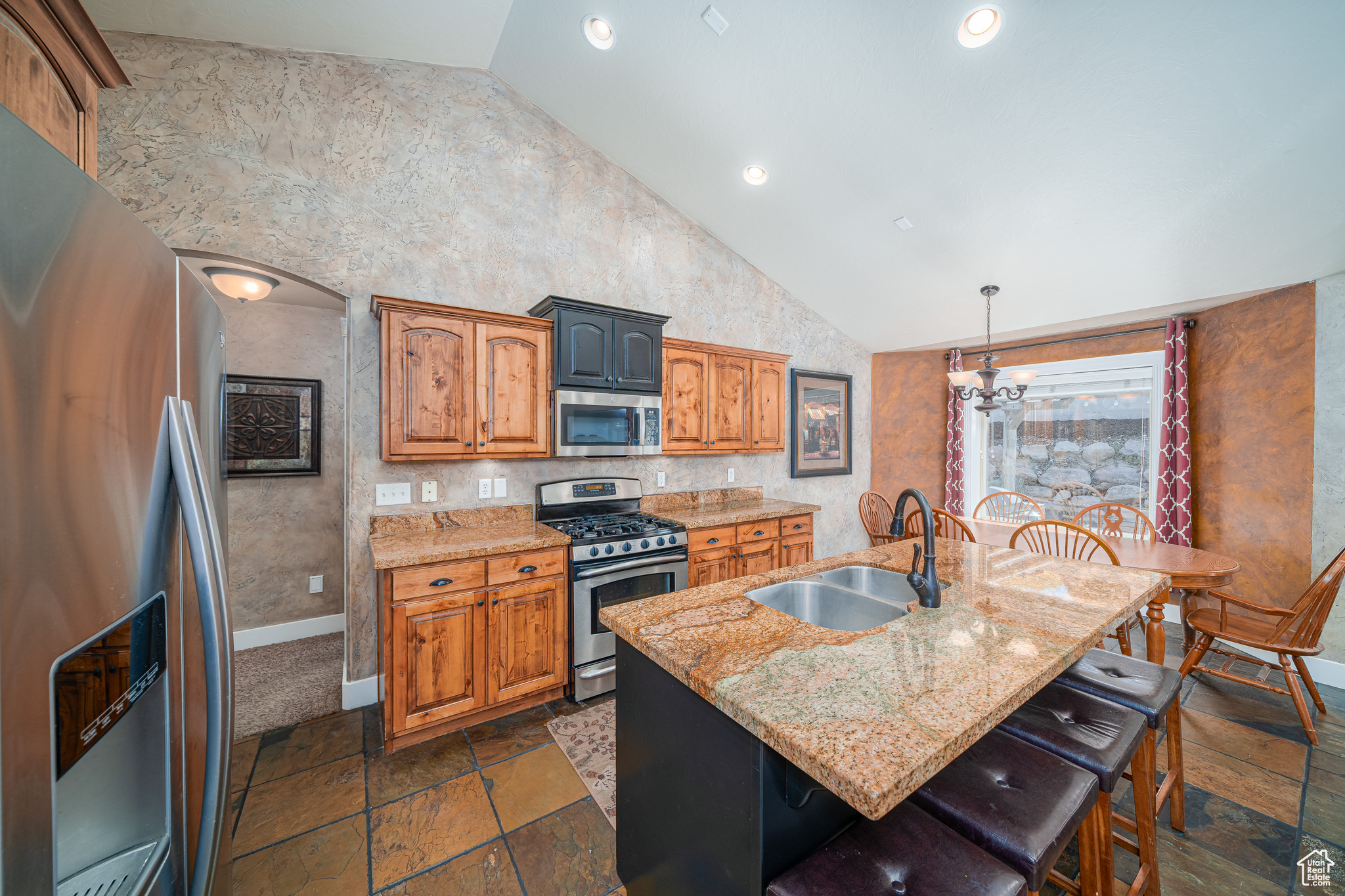 Kitchen with stainless steel appliances, a center island with sink, tasteful backsplash, sink, and a breakfast bar