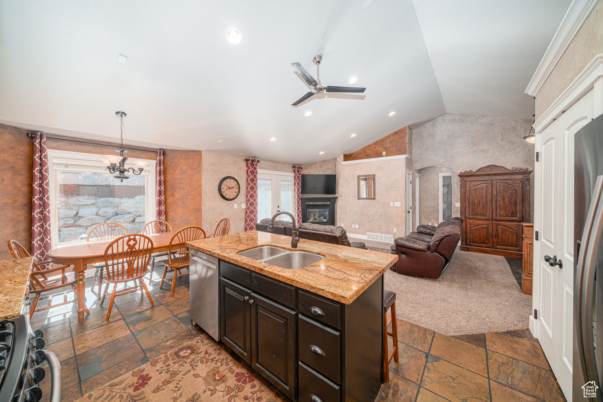 Kitchen featuring a center island with sink, sink, a wealth of natural light, and ceiling fan with notable chandelier