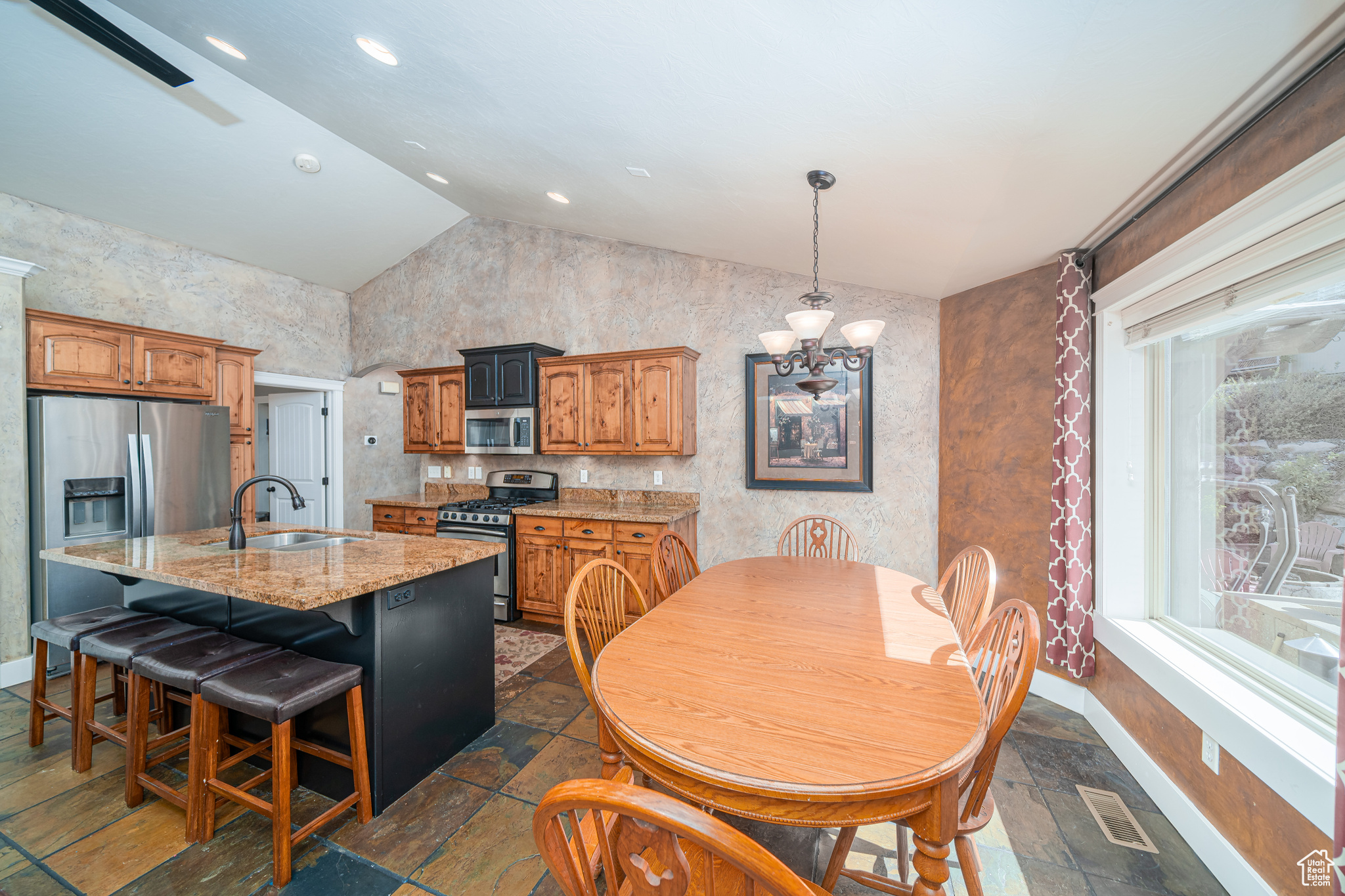 Dining room featuring dark tile floors, sink, vaulted ceiling, and an inviting chandelier