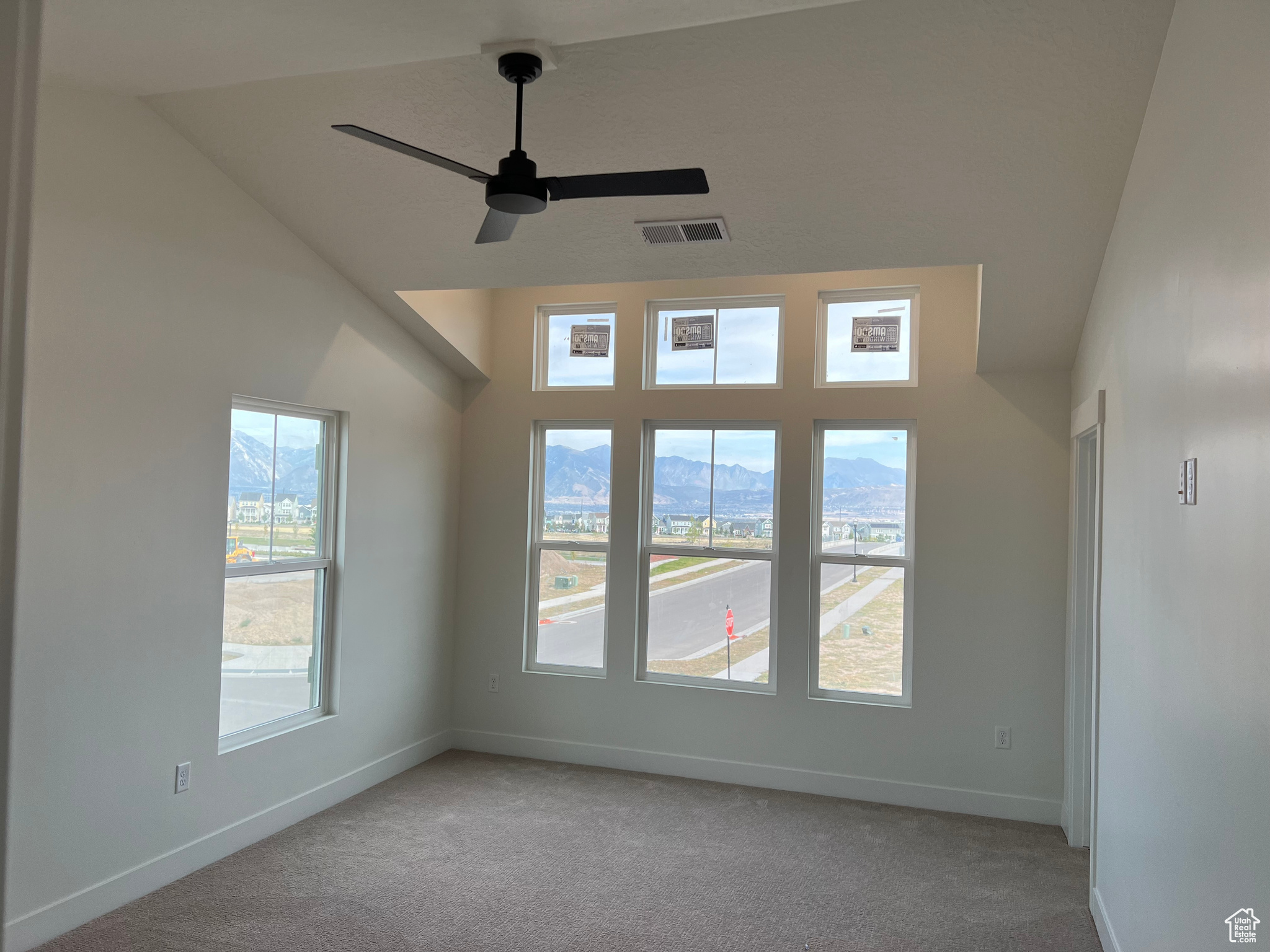 Carpeted spare room featuring vaulted ceiling and ceiling fan