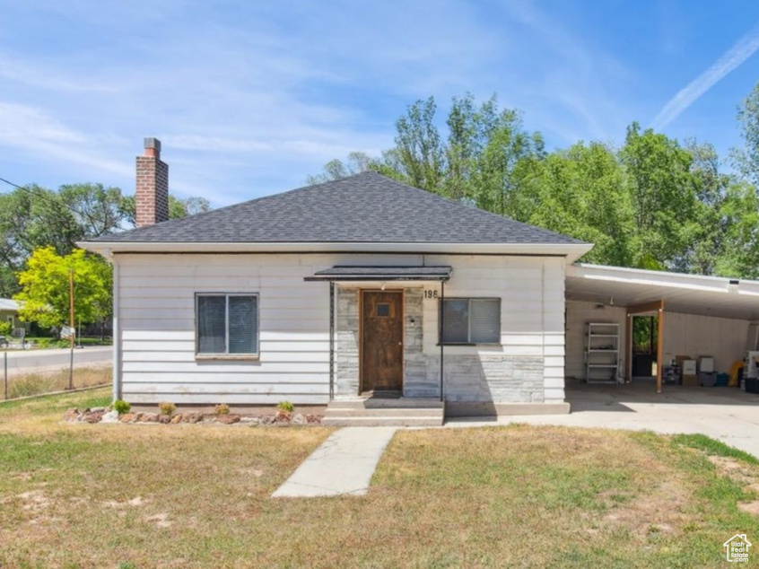 View of front facade with a front yard and a carport