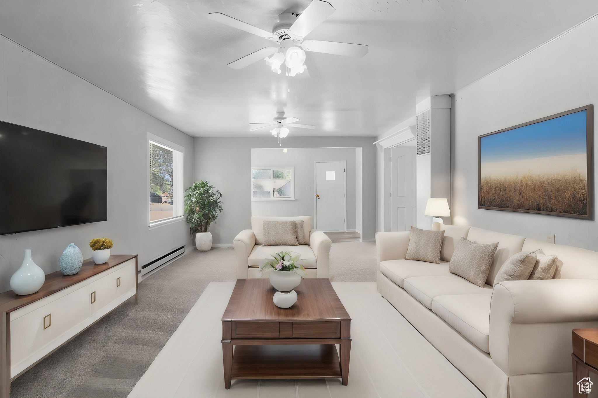 Living room with baseboard heating, carpet floors, and ceiling fan