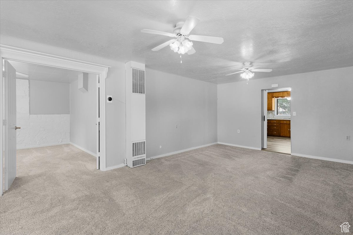 Carpeted empty room featuring a textured ceiling and ceiling fan