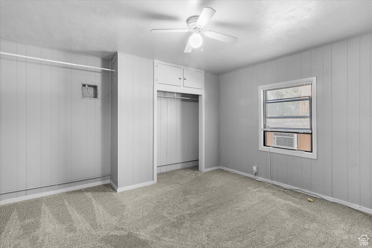 Unfurnished bedroom featuring cooling unit, light carpet, ceiling fan, and a textured ceiling