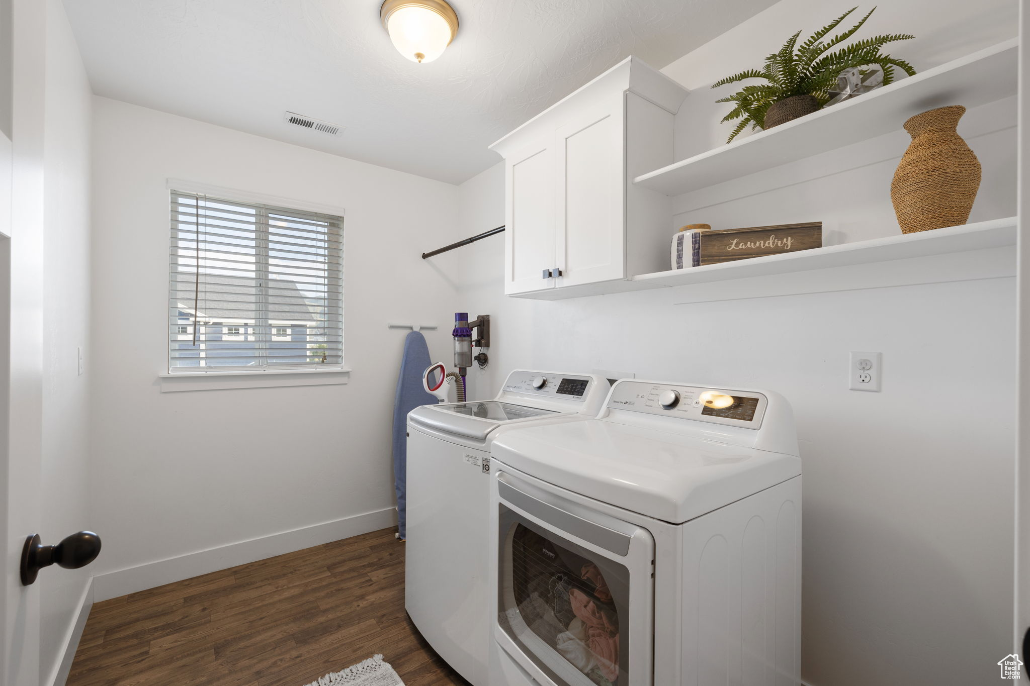 Laundry area with washer and dryer, cabinets, and dark hardwood / wood-style floors