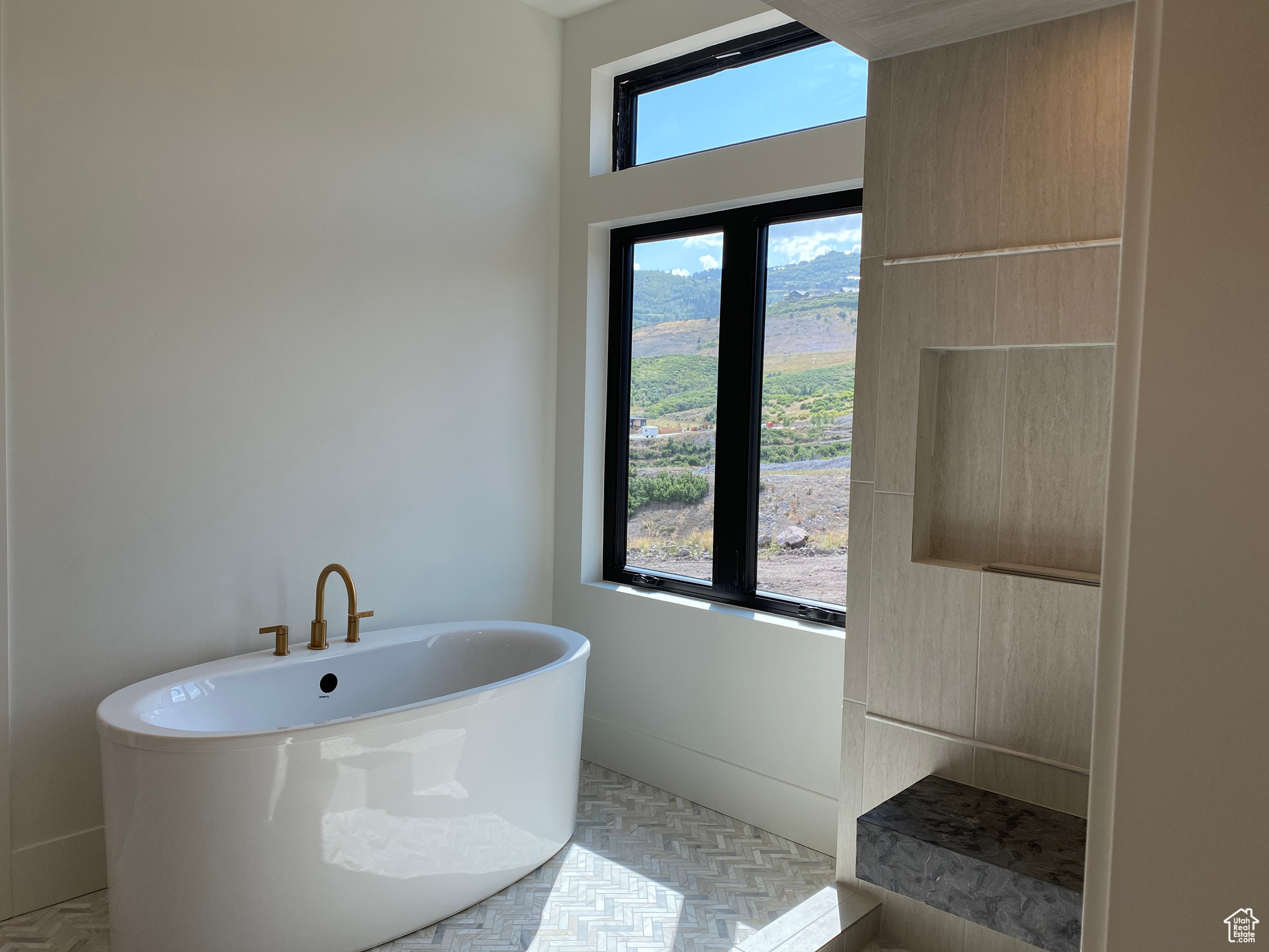 Bathroom featuring parquet floors, plenty of natural light, and a tub