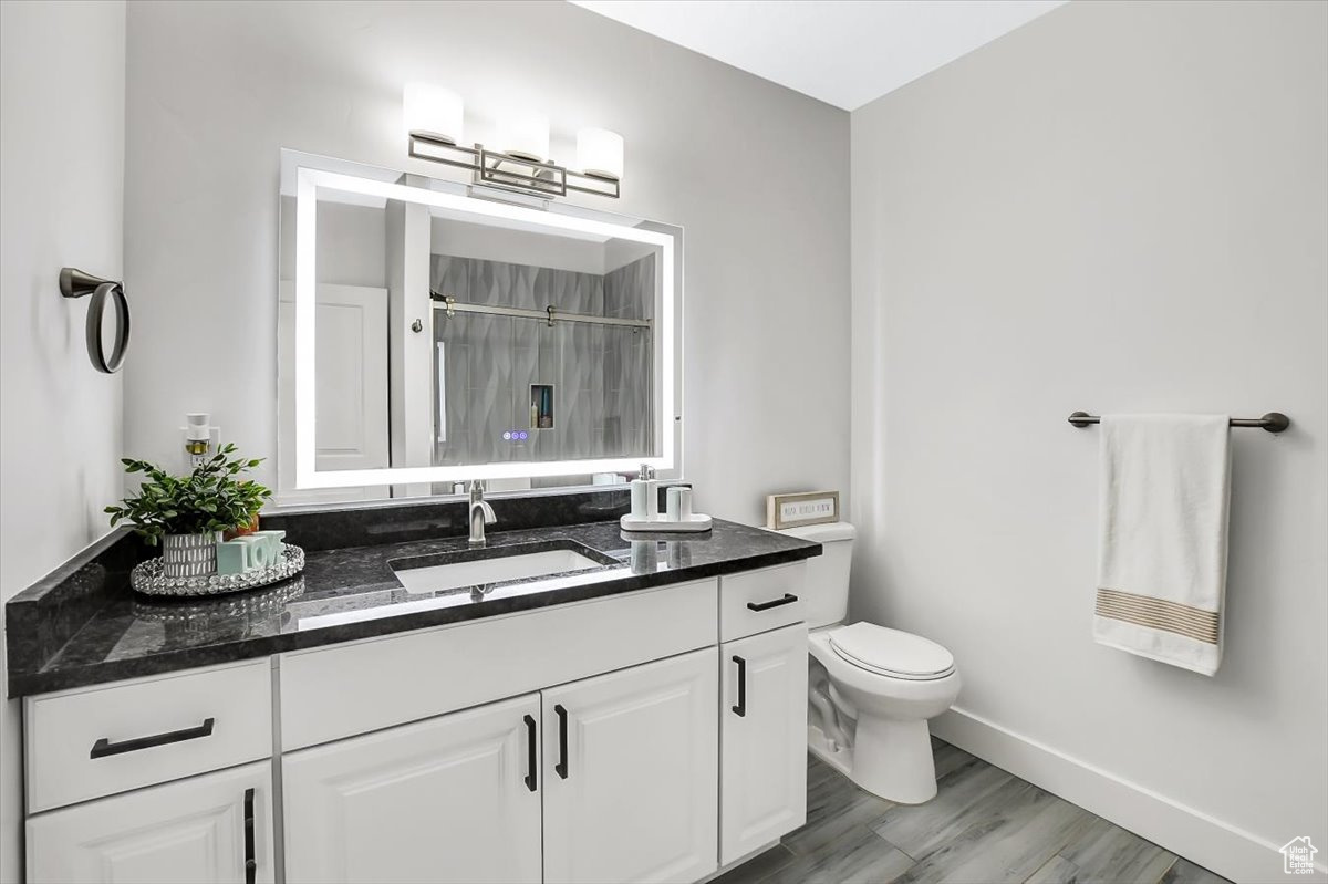 Bathroom with large vanity, toilet, and hardwood / wood-style floors