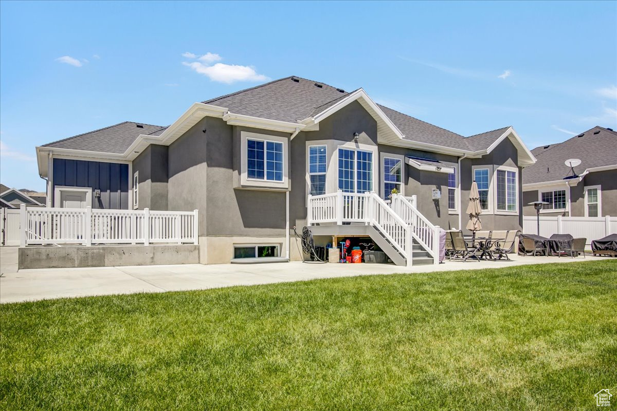 Back of house with a lawn and a patio