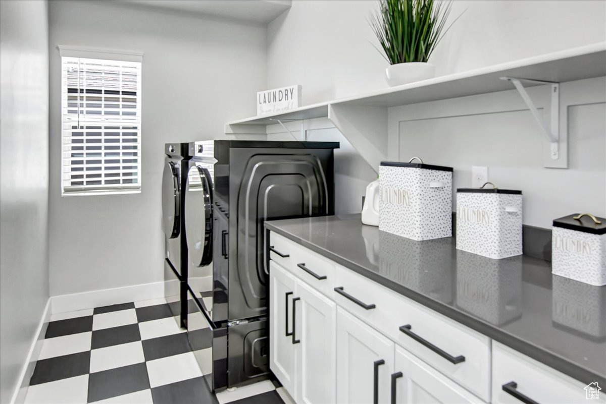 Washroom featuring washer and clothes dryer, cabinets, and light tile floors