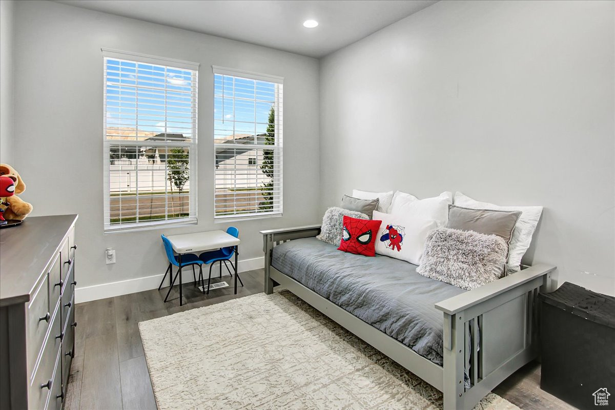 Bedroom featuring dark wood-type flooring and multiple windows