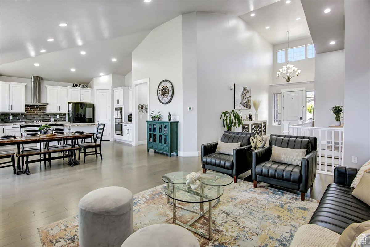 Living room with high vaulted ceiling, light wood-type flooring, and a chandelier