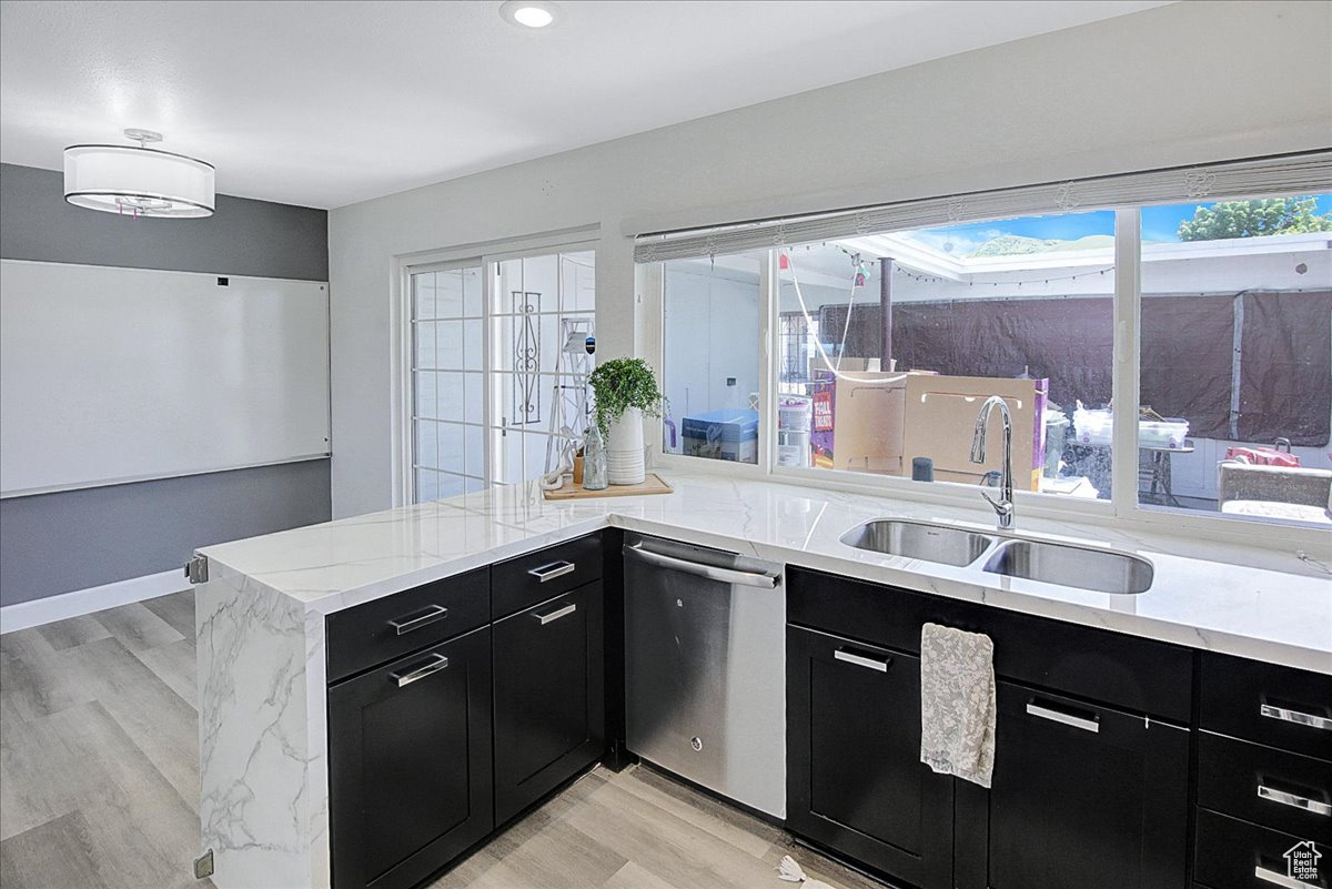 Kitchen with dishwasher, sink, light hardwood / wood-style floors, and kitchen peninsula