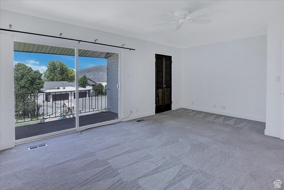 Carpeted spare room with a mountain view and ceiling fan