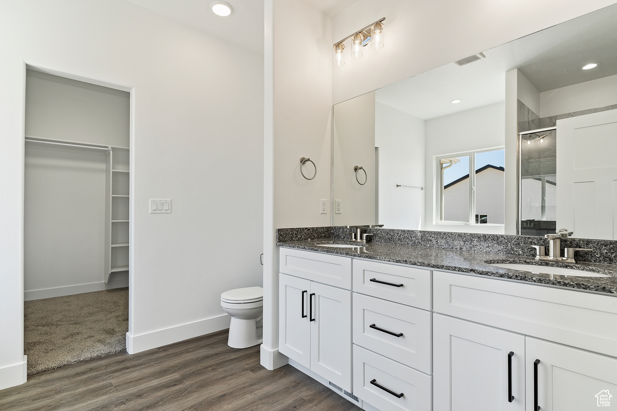 Bathroom with double vanity, toilet, and hardwood / wood-style floors