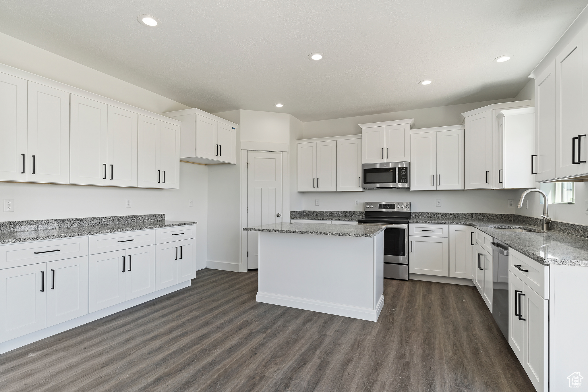 Kitchen featuring white cabinets, dark hardwood / wood-style flooring, stainless steel appliances, a center island, and sink