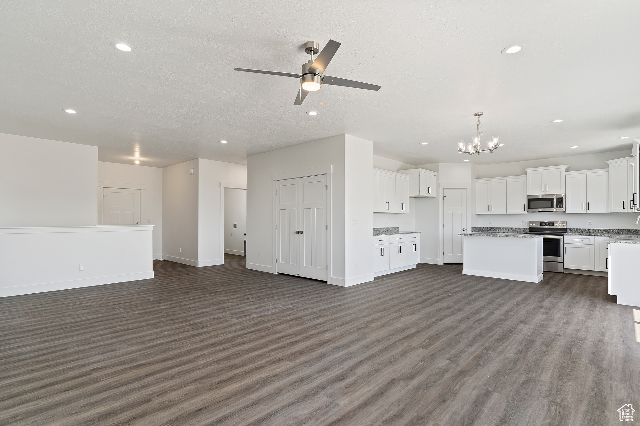 Unfurnished living room with dark hardwood / wood-style floors and ceiling fan with notable chandelier