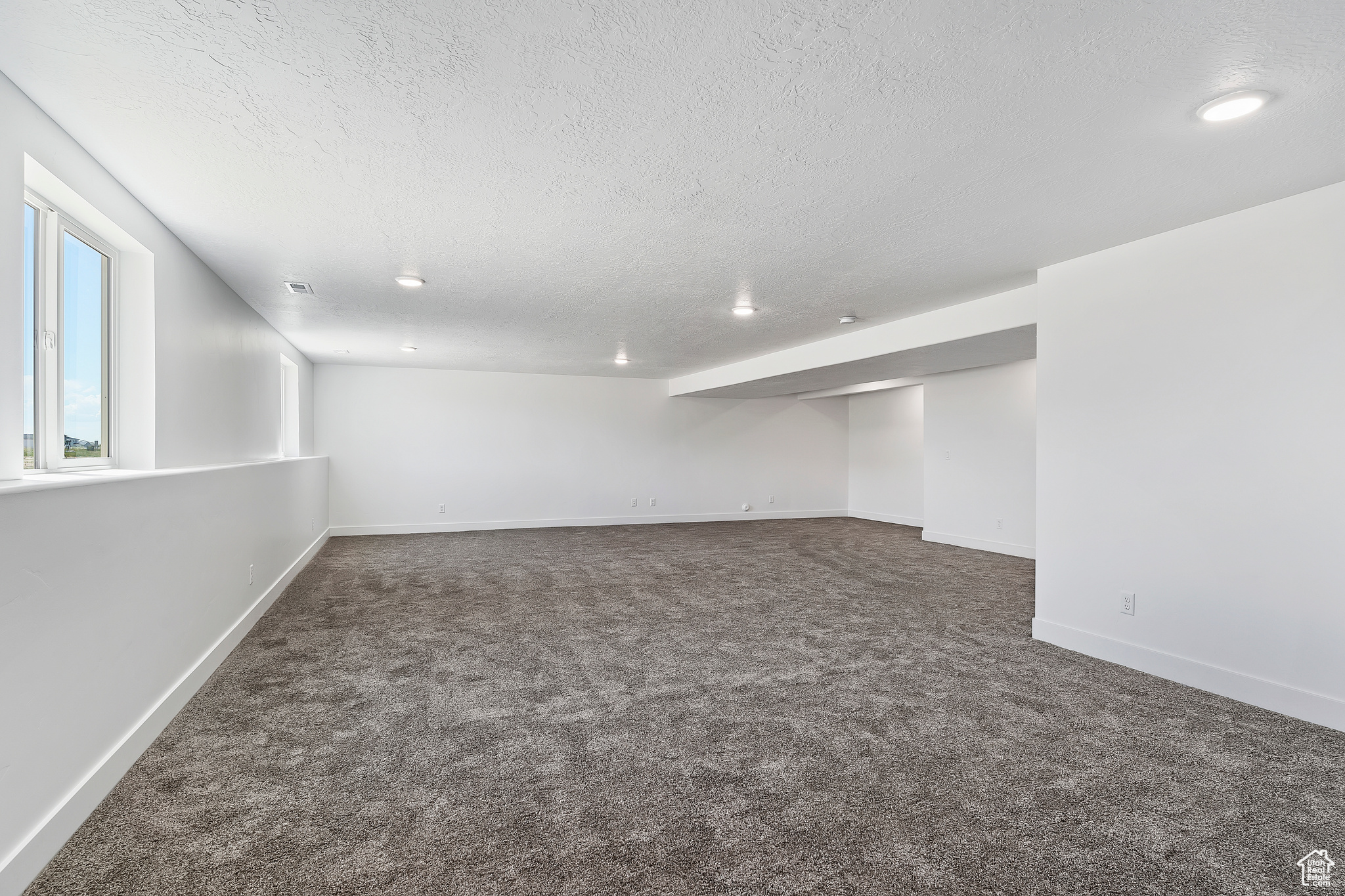 Empty room featuring a textured ceiling and dark carpet