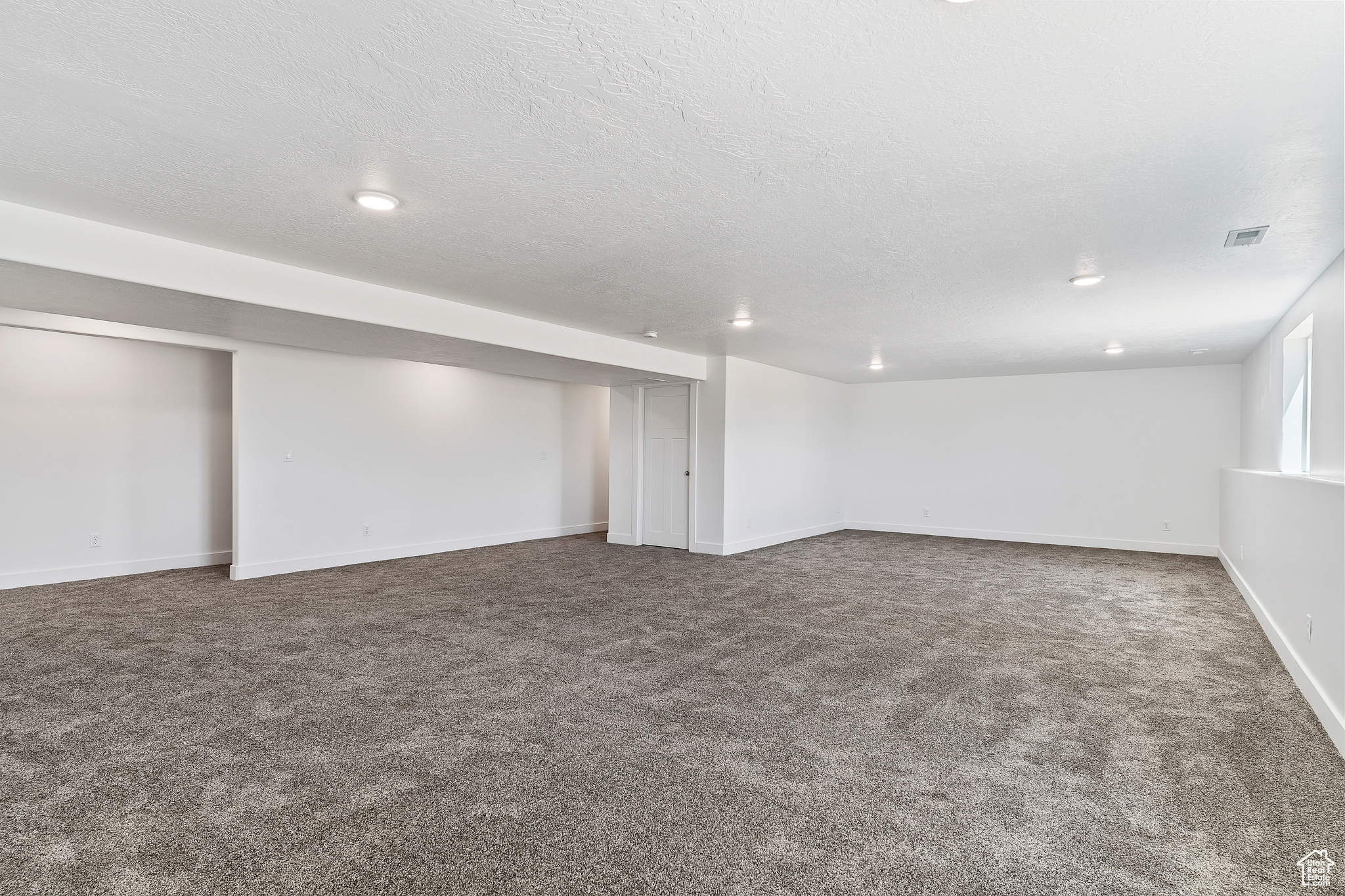 Basement with a textured ceiling and carpet floors