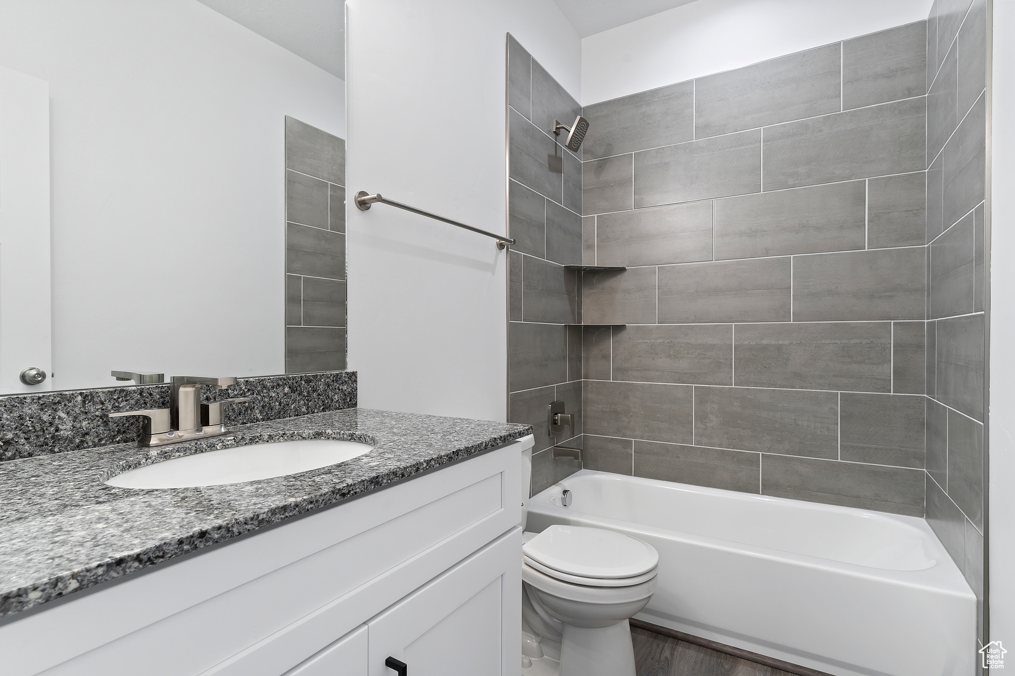 Full bathroom with tiled shower / bath, oversized vanity, hardwood / wood-style flooring, and toilet