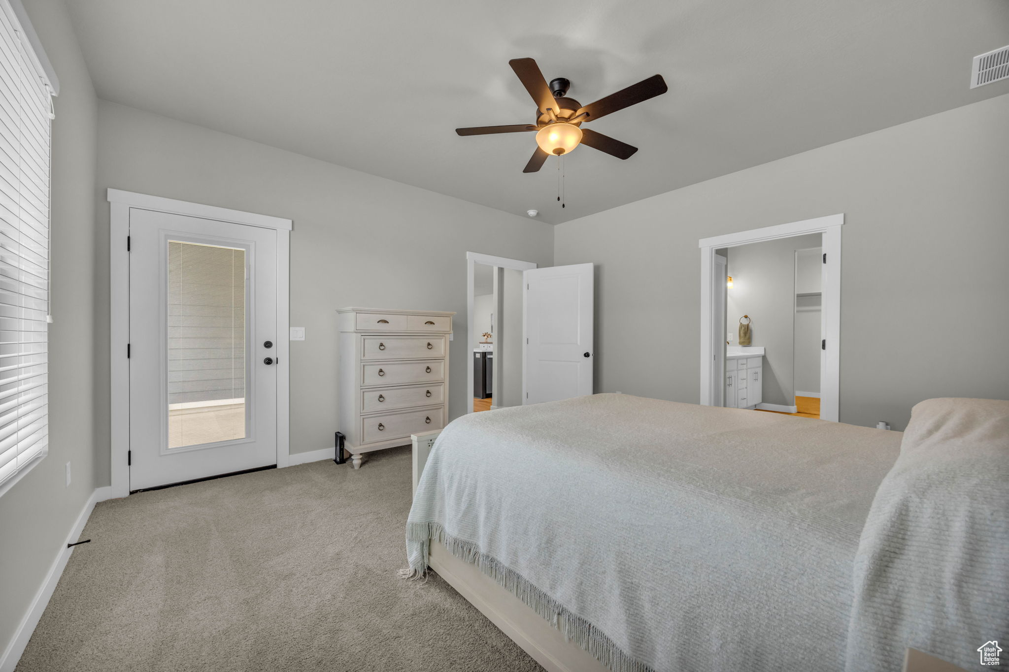 Carpeted bedroom featuring ensuite bathroom, ceiling fan, access to exterior, and multiple windows