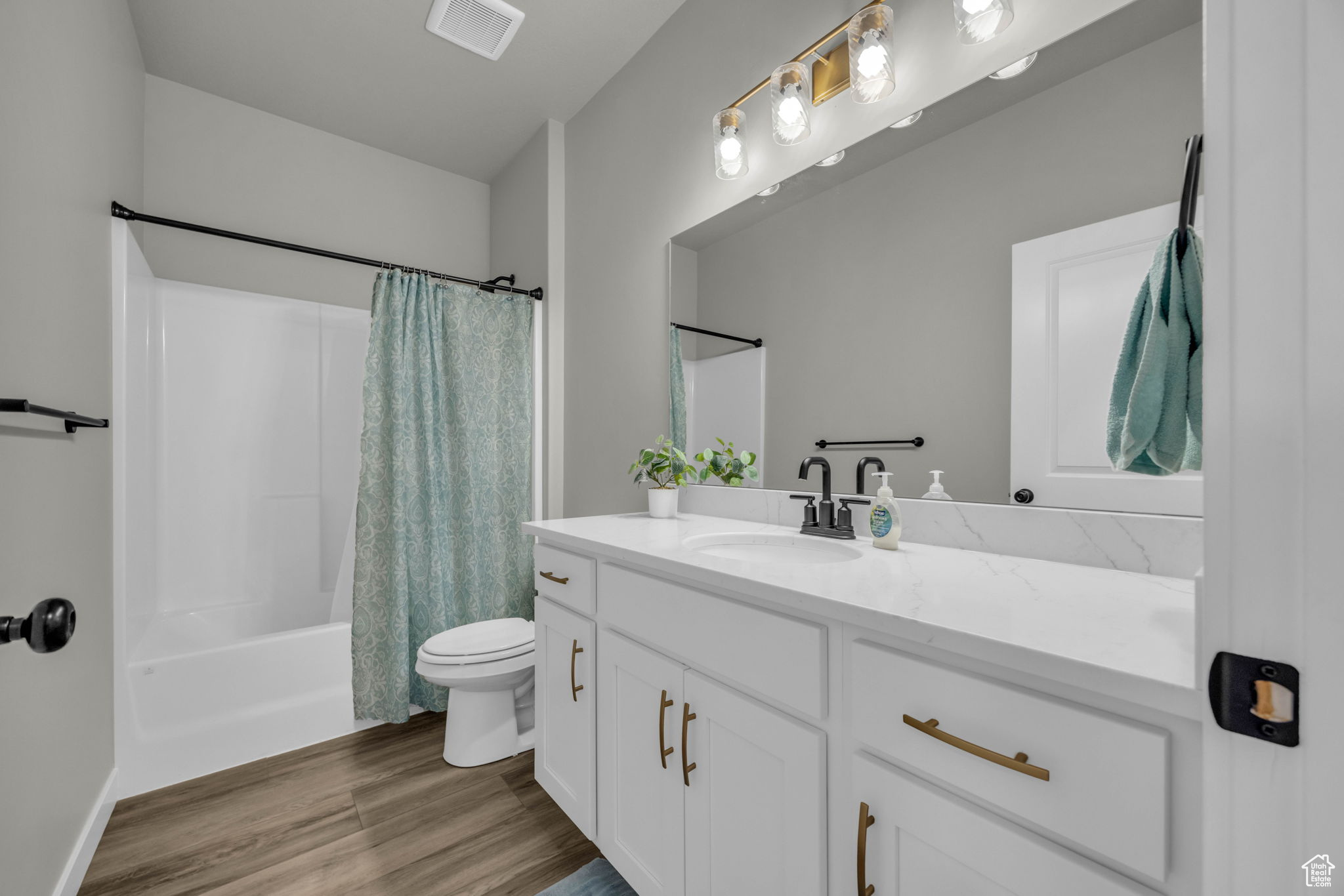 Full bathroom featuring wood-type flooring, oversized vanity, toilet, and shower / bath combination with curtain