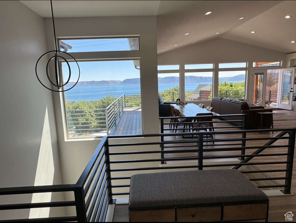 Staircase featuring plenty of natural light, hardwood / wood-style floors, lofted ceiling, and a water view