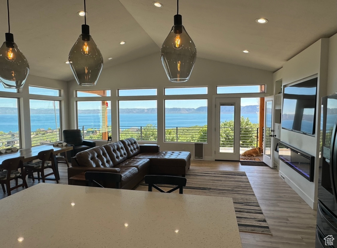 Living room with high vaulted ceiling, a water view, and hardwood / wood-style floors