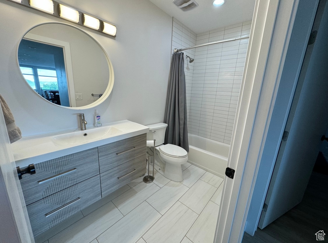 Lower level Full bathroom with shower / bath combo with shower curtain, vanity, toilet, and tile floors