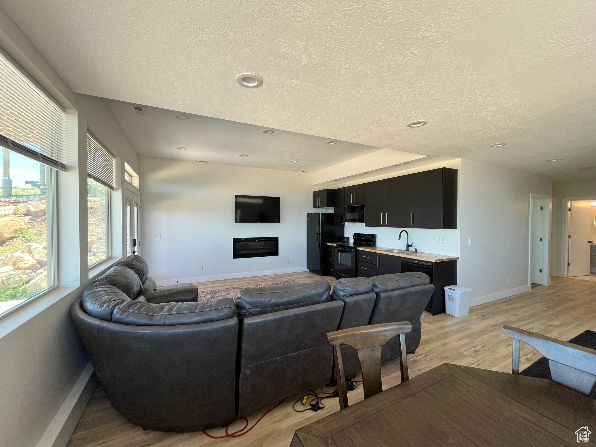 Kitchen/ Living room featuring light hardwood / wood-style floors, sink, and a textured ceiling on lower level