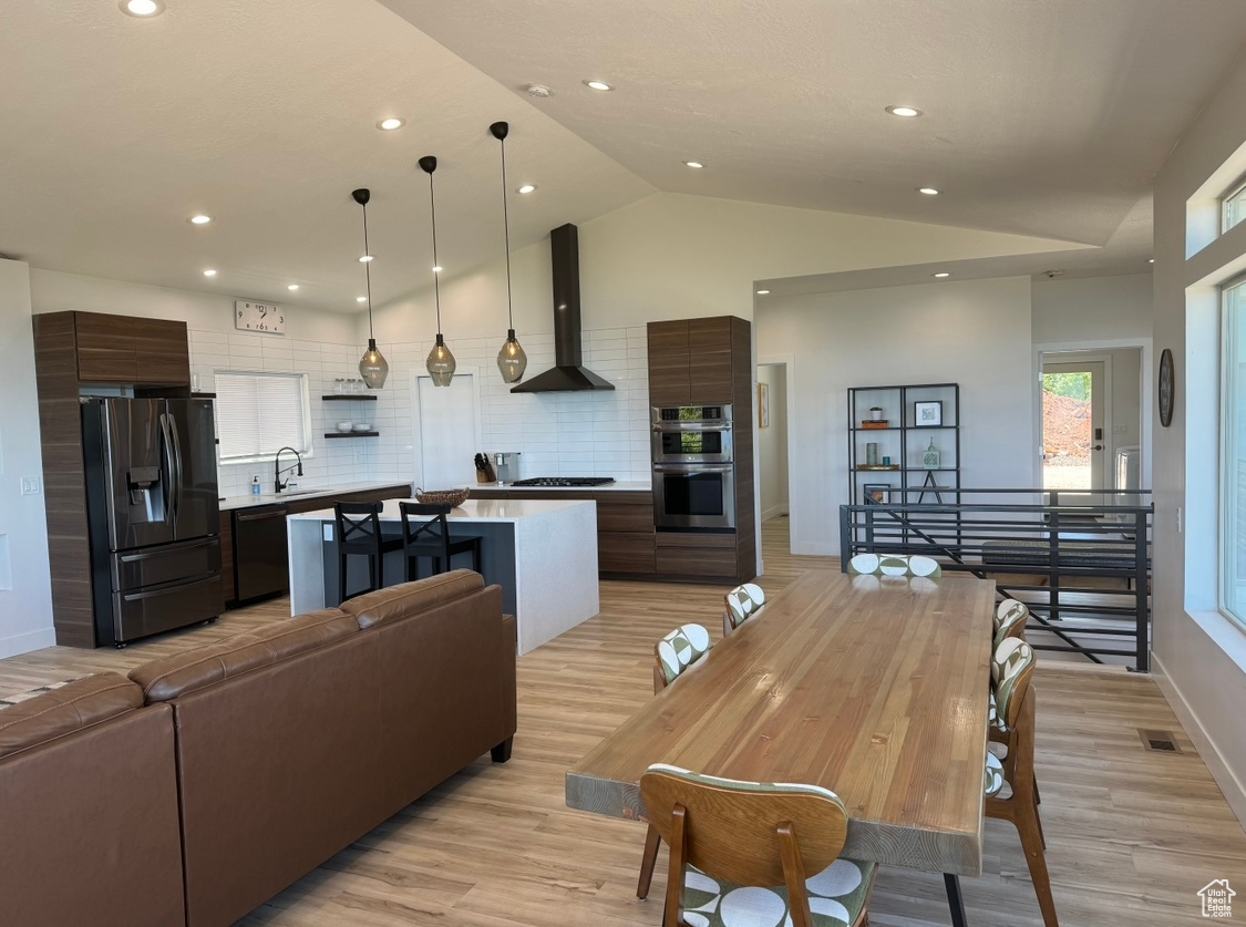 Dining room featuring sink, lofted ceiling, and light hardwood / wood-style flooring