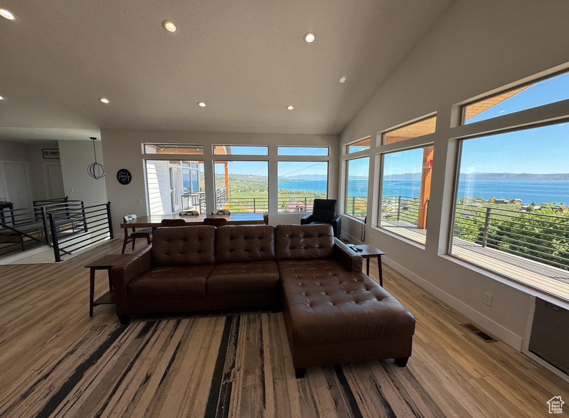 Living room with high vaulted ceiling, light wood-type flooring, and a water view