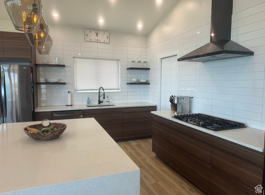 Kitchen with black appliances, sink, tasteful backsplash, and wall chimney exhaust hood