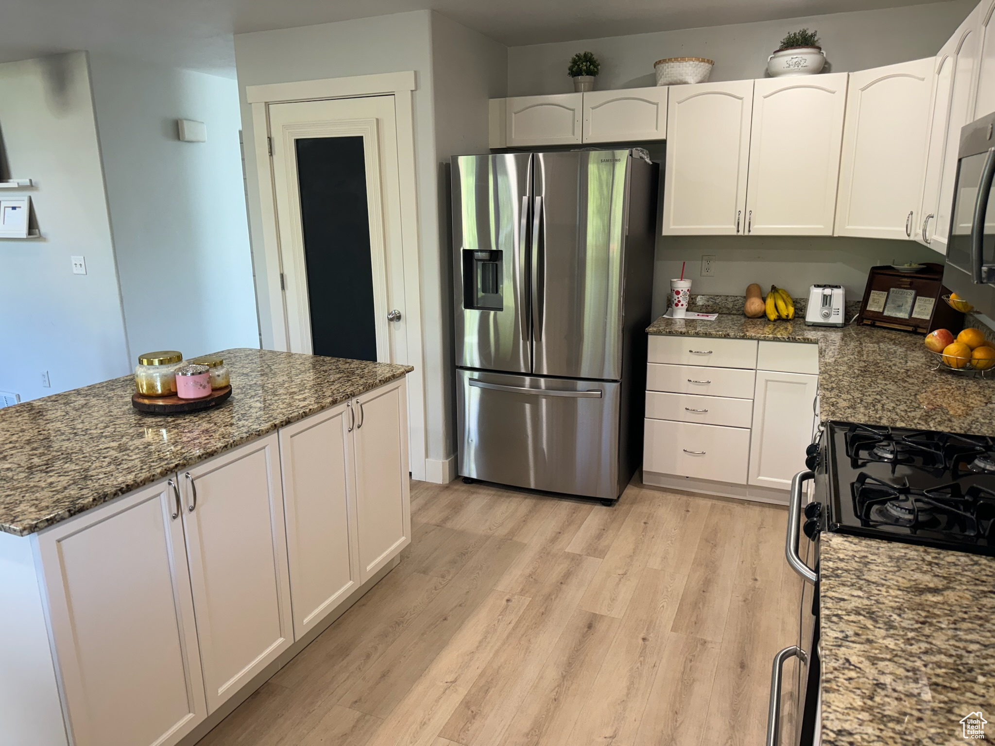 Kitchen featuring waterproof vinyl floor, Granite Countertops, Single Basin Sink with Sprayer, a kitchen island, a breakfast bar, and stainless steel appliances