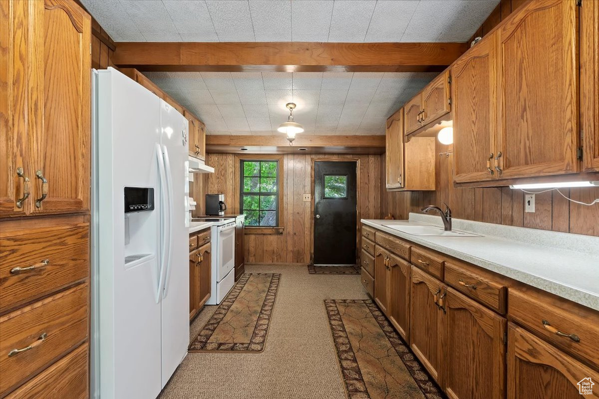 Kitchen with beamed ceiling, sink, and white appliances