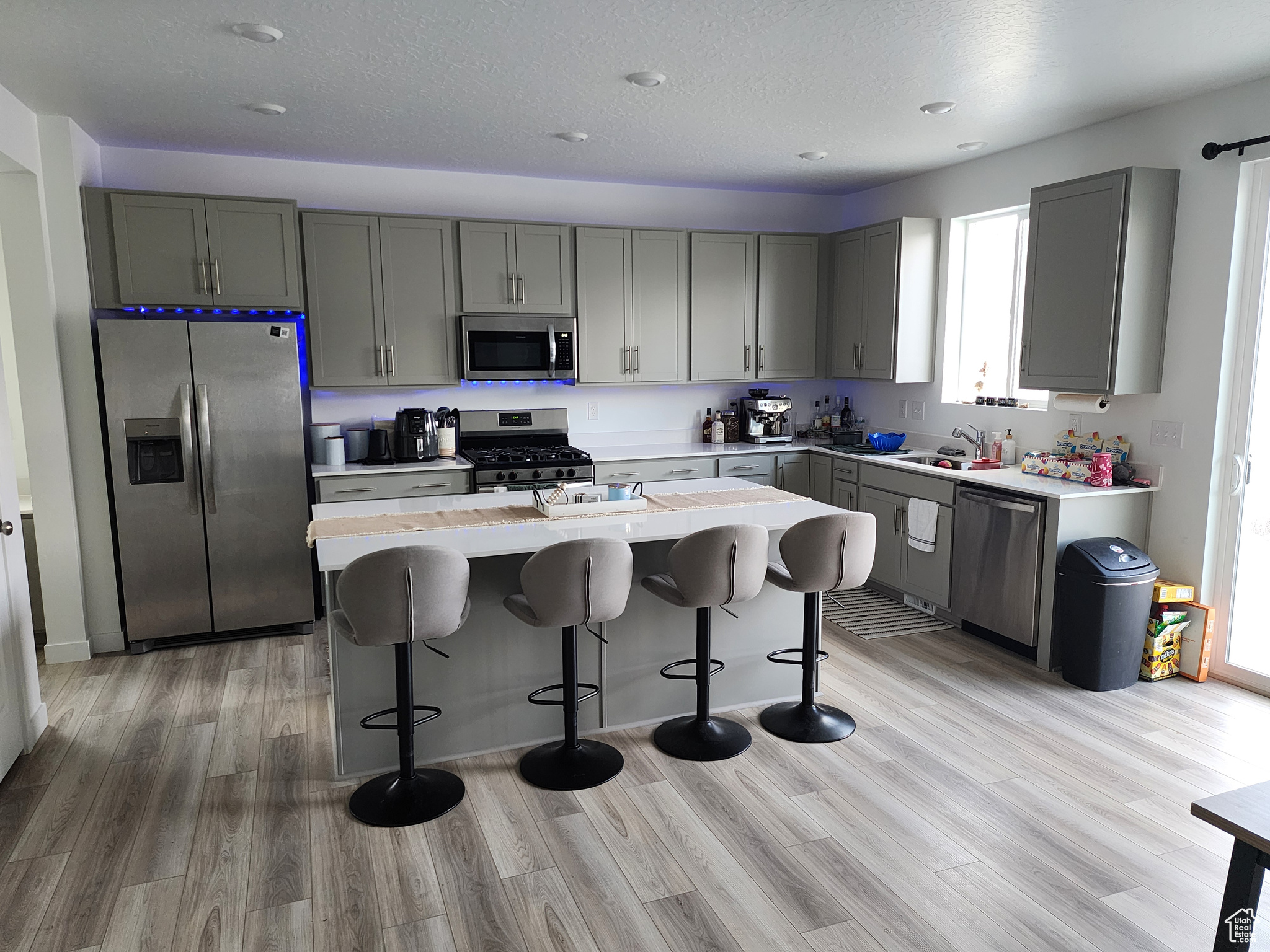 Kitchen with stainless steel appliances, light hardwood / wood-style floors, a kitchen island, and a breakfast bar