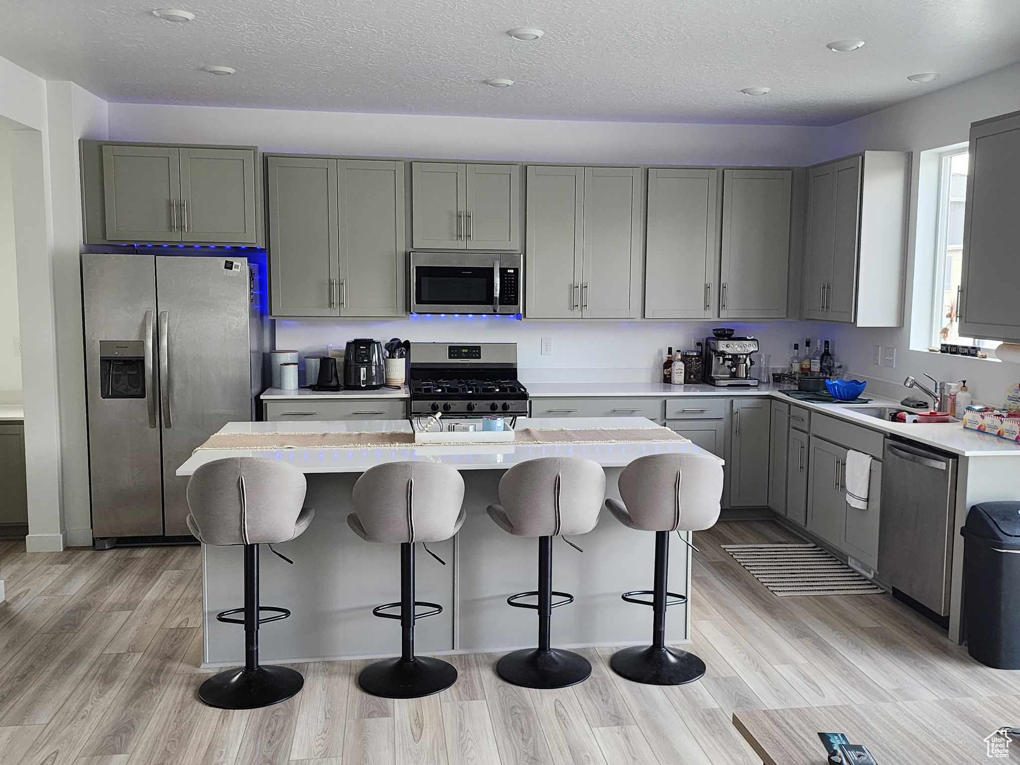 Kitchen featuring stainless steel appliances, a kitchen bar, a center island, and light hardwood / wood-style floors