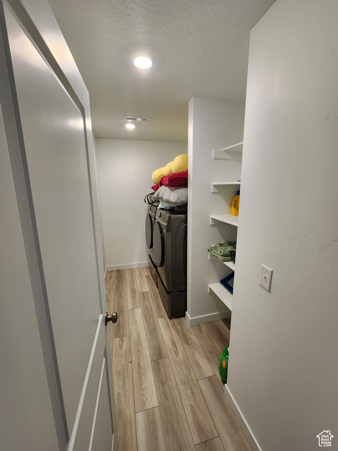 Clothes washing area featuring washing machine and dryer and light hardwood / wood-style flooring