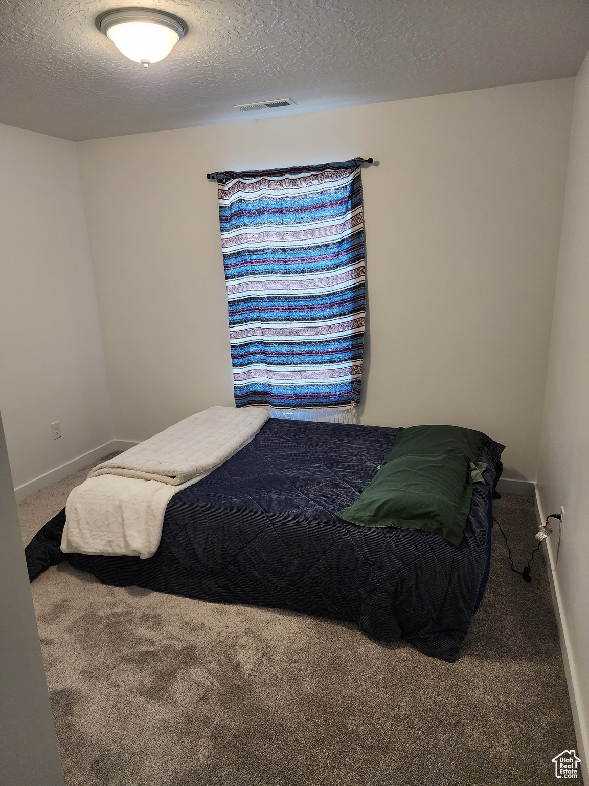 Bedroom with dark carpet and a textured ceiling