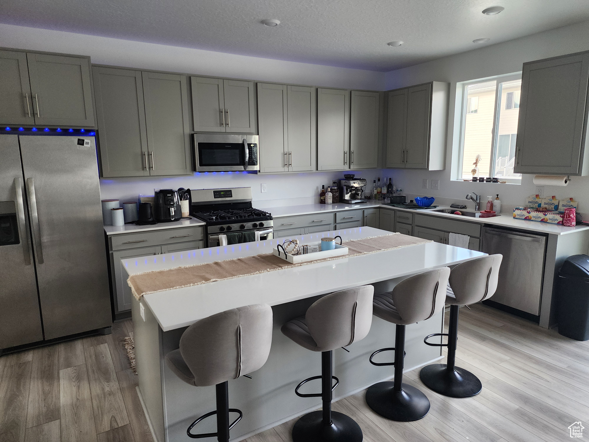 Kitchen with stainless steel appliances, a kitchen breakfast bar, a center island, and light hardwood / wood-style floors