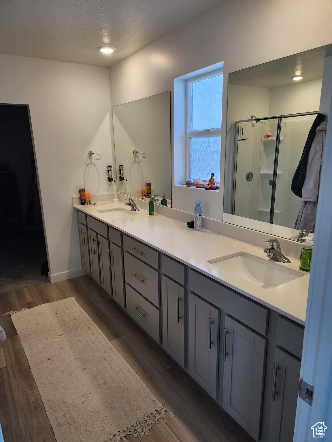 Bathroom with hardwood / wood-style floors, walk in shower, and double vanity