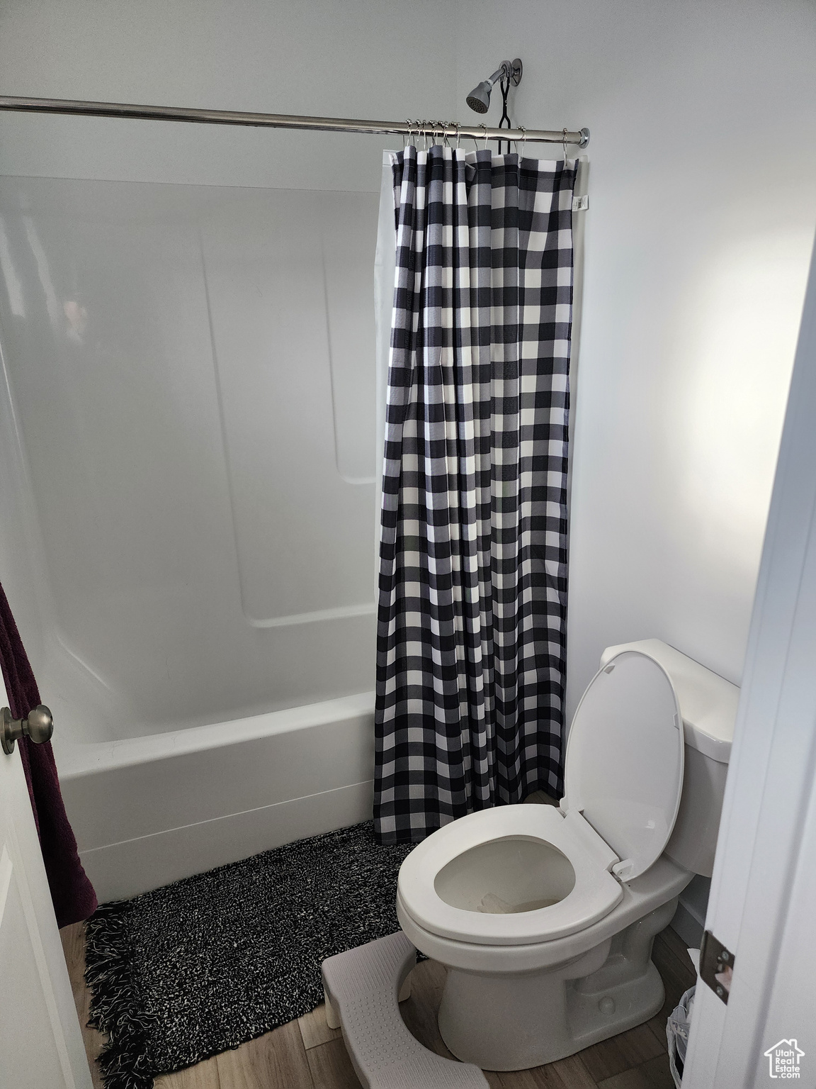 Bathroom with shower / bathtub combination with curtain, hardwood / wood-style flooring, and toilet