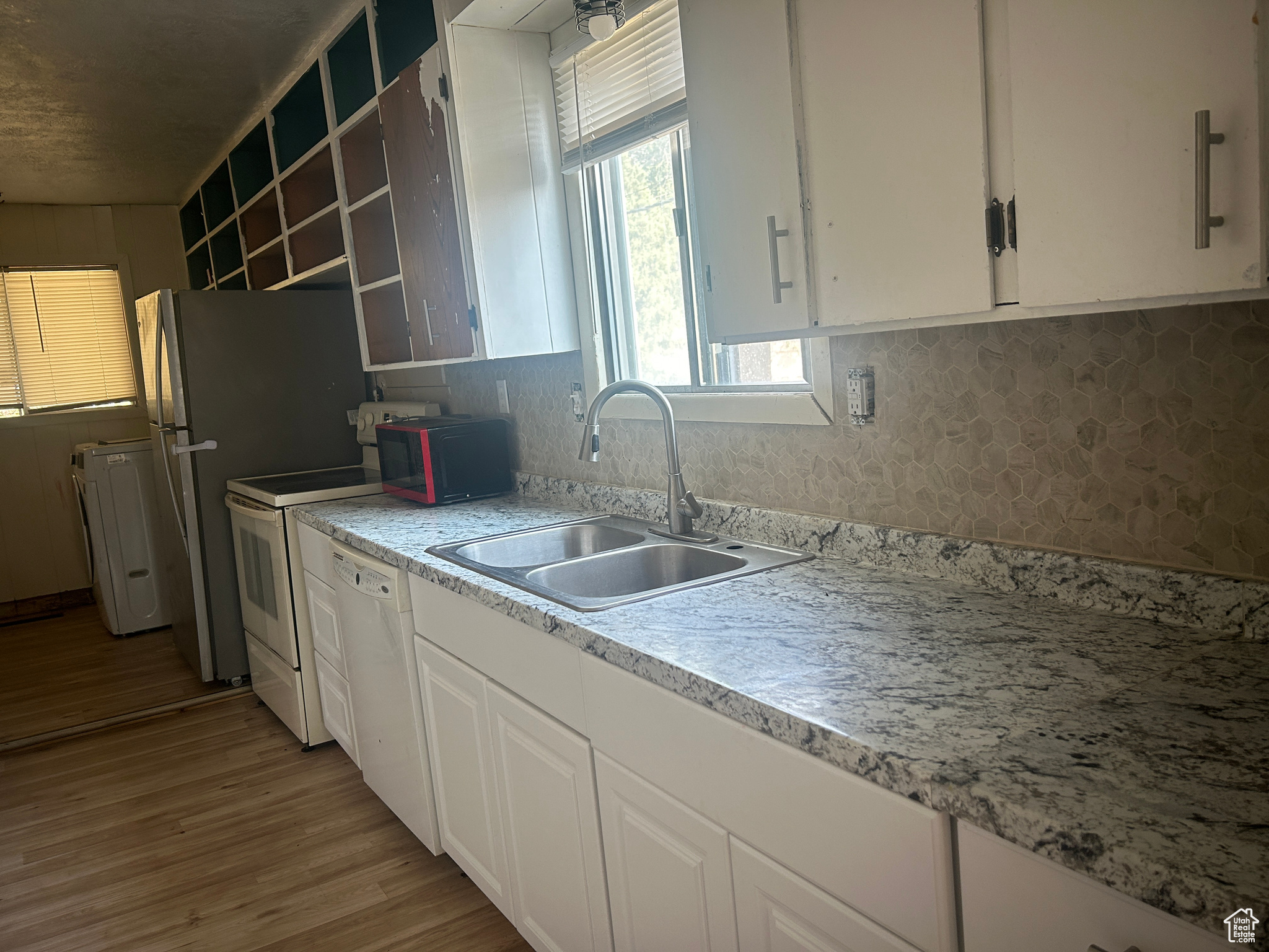 Kitchen featuring light hardwood / wood-style floors, sink, white cabinetry, and white dishwasher