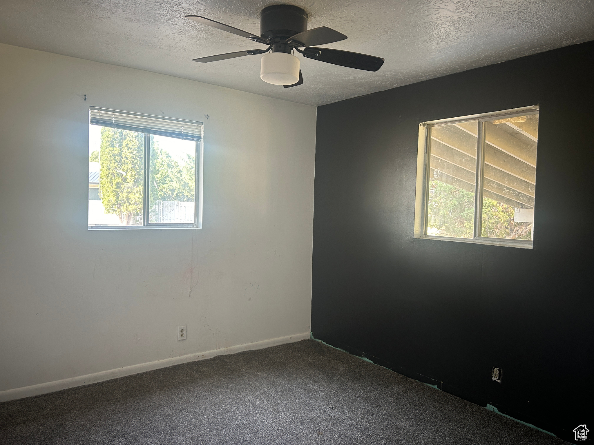 Empty room featuring a textured ceiling, ceiling fan, and carpet flooring