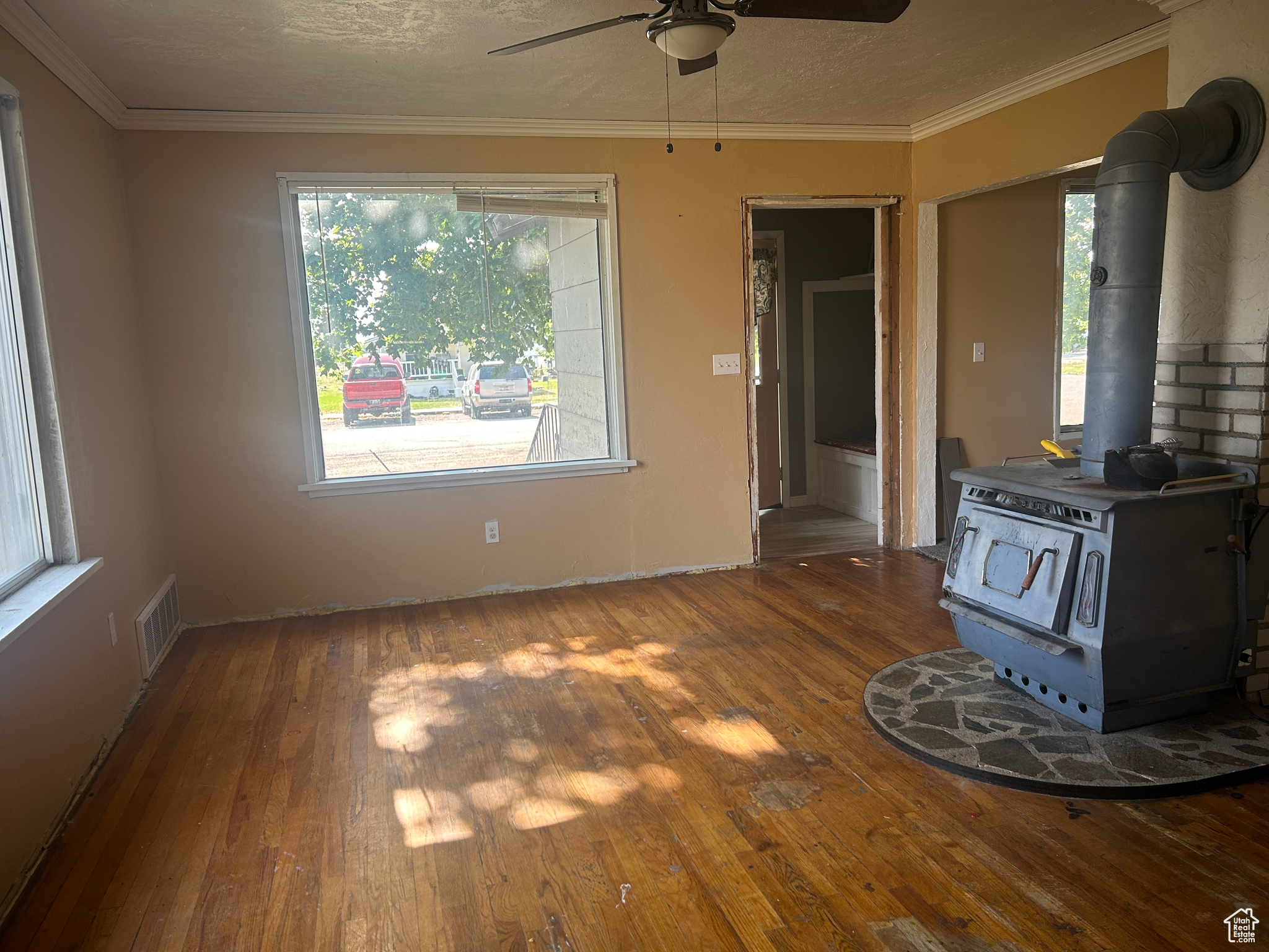 Unfurnished living room with dark hardwood / wood-style floors, ceiling fan, and a wood stove