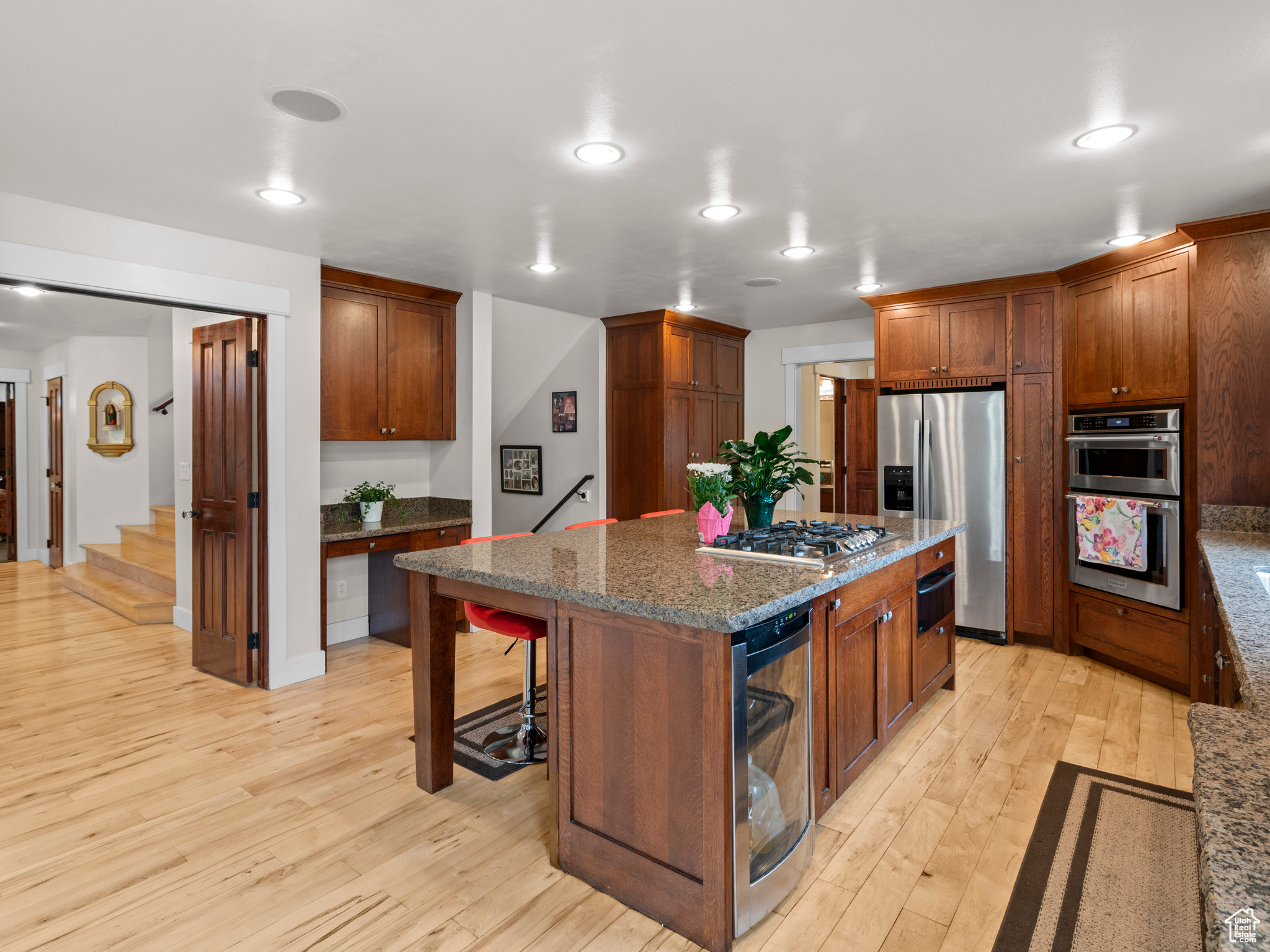 Kitchen with a kitchen island, stainless steel appliances, light hardwood flooring, dark granite counters, and a breakfast bar area