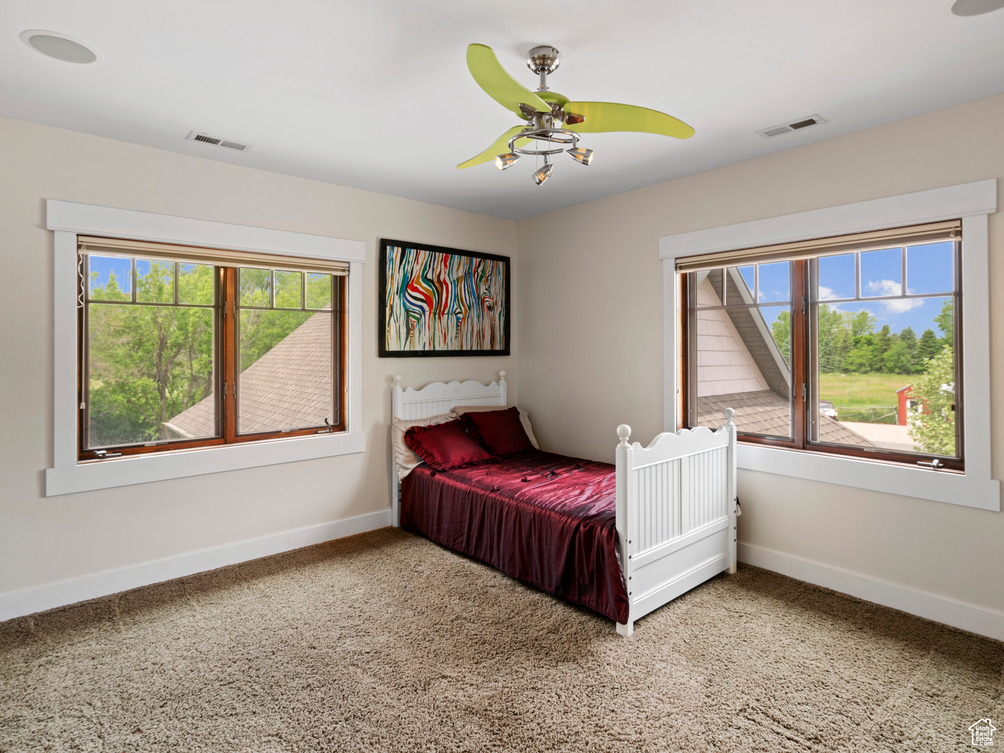 Carpeted bedroom with ceiling fan and multiple windows