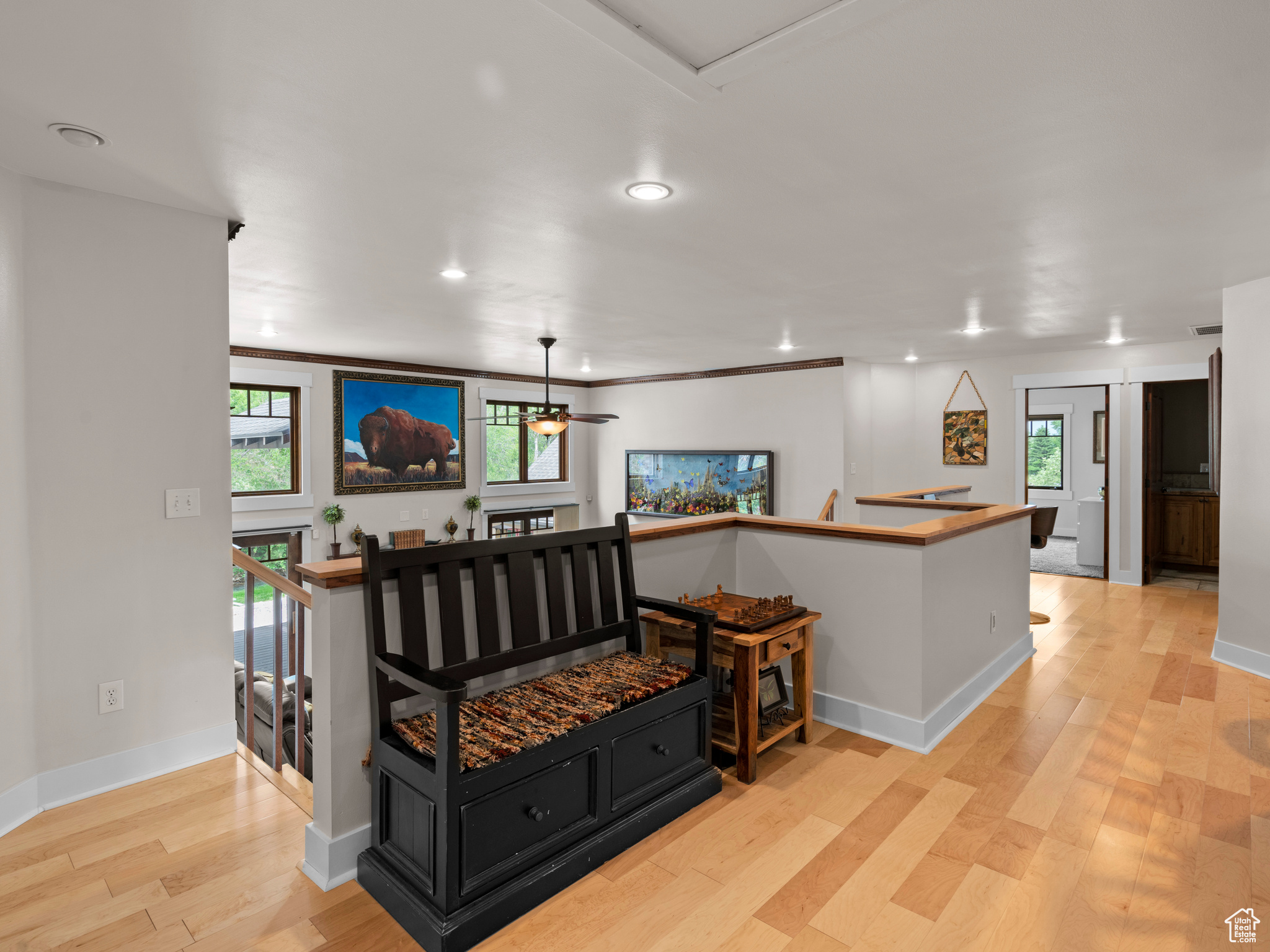 Landing with ceiling fan, hardwood flooring, seating area, and ornamental molding